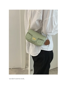 Detail of mint green quilted leather bag with gold chain strap and heart charm