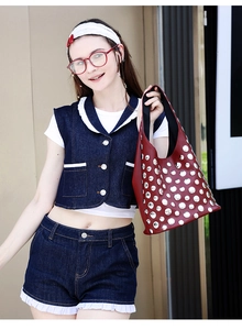 Macro shot of red leather tote bag featuring dense silver studs with a stylish model