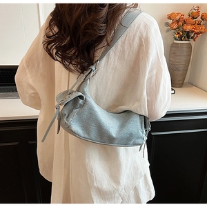 Lifestyle view of a denim textured crescent shoulder bag with soft side knot detailing