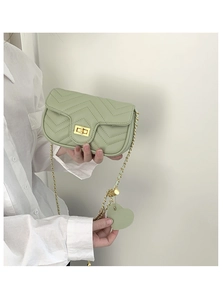 Detail of light green chevron quilted mini flap bag with gold chain and heart charm
