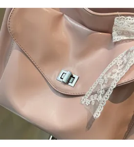 Detail of pink leather tote bag featuring a silver rectangular twist lock and lace ribbon