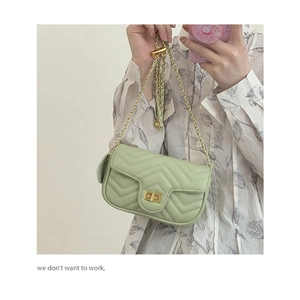 Close-up of light green quilted leather handbag with gold chain strap and turn-lock closure