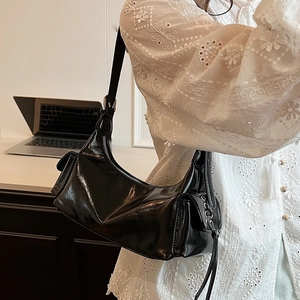 Schwarze Retro-Umhängetasche aus Kunstleder mit Metallic-Details auf weißem Spitzenoberteil