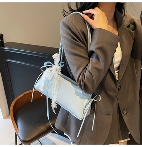 Light blue baguette bag with white lace bows and ballet style ribbons shown on shoulder