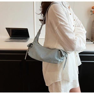 Chic light blue denim underarm bag styled in a trendy minimalist office setting