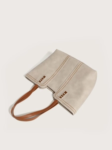 Detail of minimalist tote bag with contrast brown stitching and woven handle accents