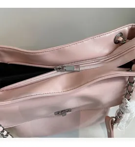 Close-up of smooth silver zipper and white lace bow detail on pink leather tote bag