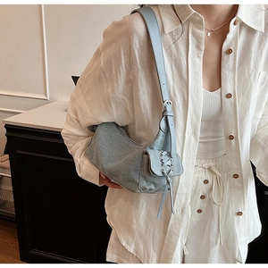 Detail of light blue denim shoulder bag with cross-lacing and metallic eyelets on side