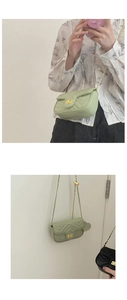 Detail of sage green quilted crossbody bag featuring a golden metallic rectangular lock