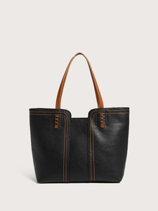 Detail view of black lychee grain leather tote bag with contrast orange-brown stitching