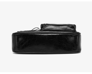 Detail of black patent leather crossbody bag showing vintage pleated texture and zipper