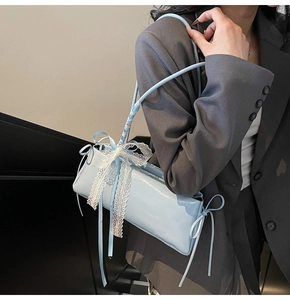 Detail of light blue patent leather shoulder bag with white lace bow and ribbon decor