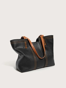 Detail of a black leather tote bag featuring orange contrast stitching and woven handle accents