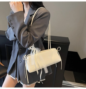 Detailed side view of white baguette bag with lace ribbon on a grey blazer outfit