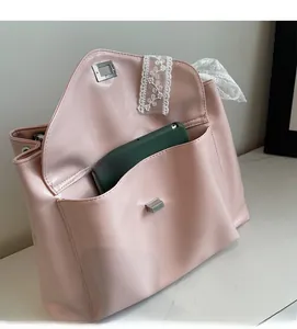 Detail of light pink glossy tote bag showing a front pocket holding a smartphone