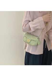 Detail of light green quilted crossbody bag with gold twist lock and heart pendant