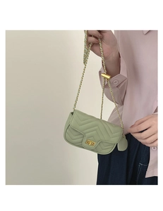 Detail of light green quilted crossbody bag with golden twist lock and chain strap