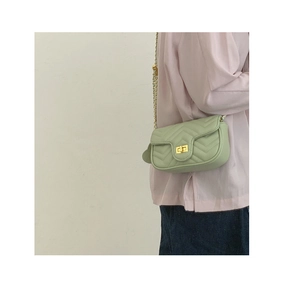 Detail of mint green quilted crossbody bag with gold chain strap on model
