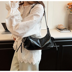 Detail view of the black glossy leather shoulder bag with side tassel drawstring accents
