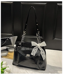 Détail du sac cabas en cuir verni noir avec nœud en dentelle blanche et fermoir rotatif