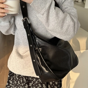 Large black hobo tote bag with silver eyelet strap shown in a daily lifestyle outfit