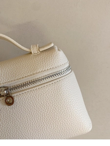 Detailansicht der weißen Lederstruktur und des silbernen Reißverschlusses der Mini-Tasche