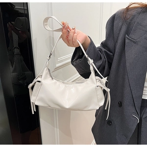 Detail of white glossy leather shoulder bag with side tassel accents and smooth zipper