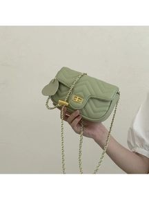 Detailed close-up of light green quilted crossbody bag with heart charm and gold chain
