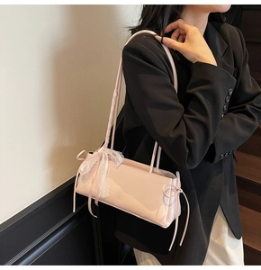 Detail of light pink baguette bag featuring delicate lace bows and long ribbon accents