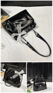 Détail macro du sac cabas noir brillant avec fermoir argenté et grand nœud en dentelle