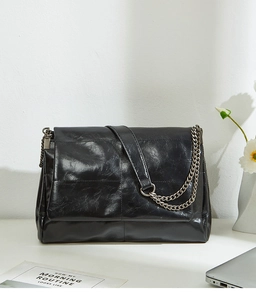 Detail of glossy black oil-wax leather texture and stylish chain strap on a flap bag