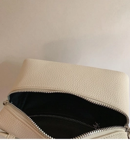 Detailaufnahme der beigen Handtasche aus genarbtem Leder mit Silber-Reißverschluss und Innenfach