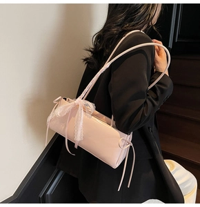 Detail of pink patent leather baguette bag with lace straps and large ribbon bow