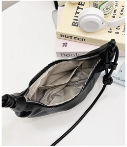 Detail view of the black croissant bag interior with herringbone lining and knot strap
