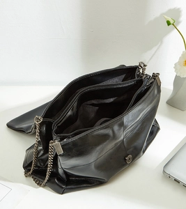 Detail view of black chain shoulder bag showing three main zipper compartments and interior