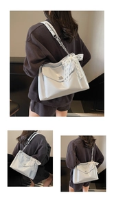 Detail of light blue patent leather tote bag with lace bow and chain strap on shoulder