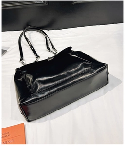 Détail du sac cabas noir brillant avec chaînes argentées et grande capacité de rangement