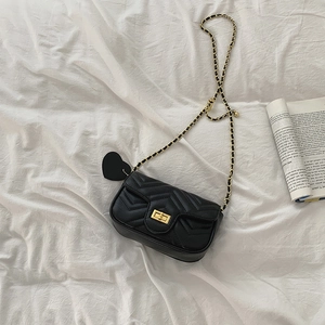 Detailed top view of black quilted crossbody bag with gold chain strap on white fabric