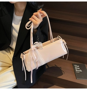 Detail of light pink patent leather shoulder bag with white lace bows in ballet style