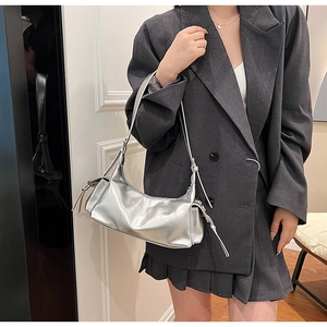 Detail of trendy metallic silver shoulder bag with side decorative drawstring ribbons