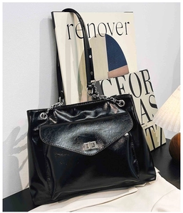 Détail d'un grand sac cabas noir brillant avec chaîne argentée et boucle en métal