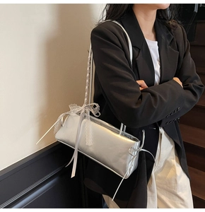 Close-up of metallic silver baguette bag with delicate white lace bow detail