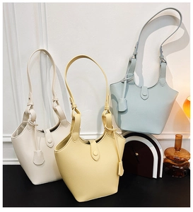 Nahaufnahme minimalistischer Beuteltaschen in Beige, Gelb und Blau mit Lychee-Ledertextur