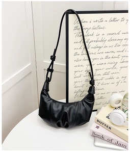Detail of black crescent croissant bag with knot strap and embossed fashion text