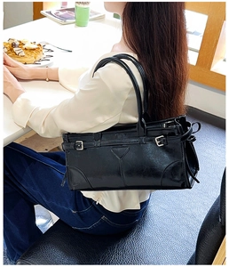 Seitenansicht einer glänzenden schwarzen Schultertasche aus Leder mit Silberschnallen