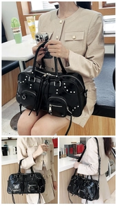 Close-up of black matte leather handbag with silver studs and multiple zippers