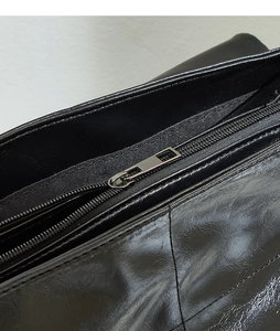 Detail shot of the smooth black leather texture and sleek silver metal zipper closure