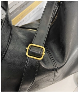 Gros plan détaillé du cuir noir grainé et de la boucle en métal doré du sac cabas