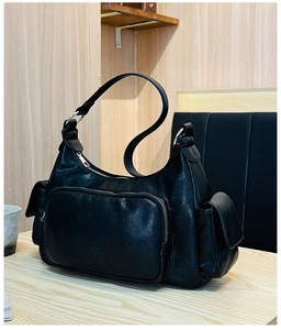 Detailed close-up of black lychee-textured leather bag with stylish gold metal zippers