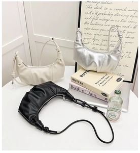 Three half-moon croissant bags in black, white, and silver on a minimalist display